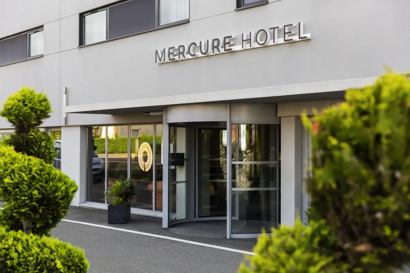 Entrée principale d'un hôtel Mercure avec des plantes en pot et des fenêtres vitrées