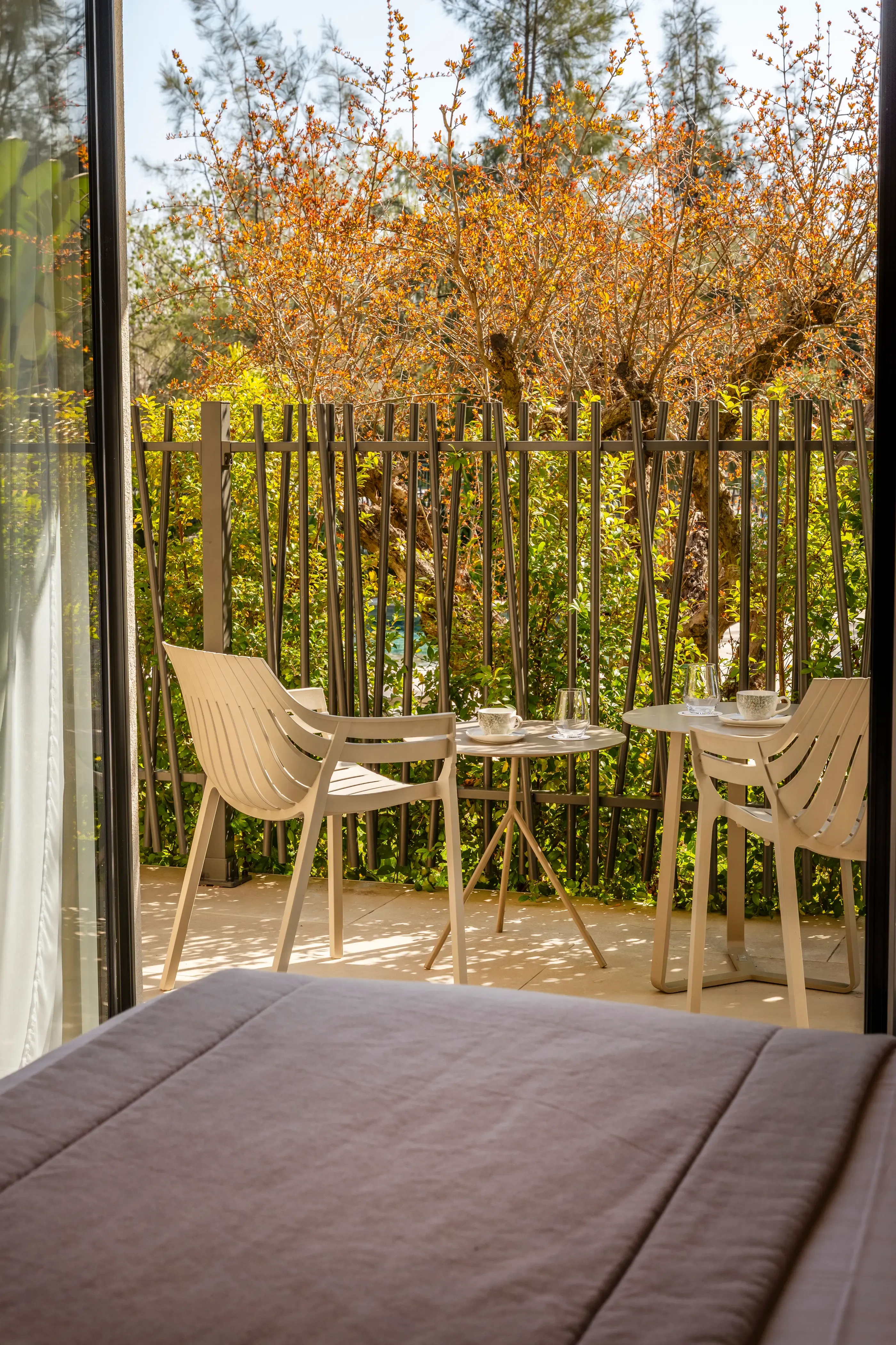 Balcon avec deux tables, chaises et une vue sur un jardin avec des plantes et des arbres